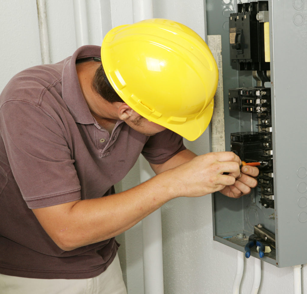 An electrician working on a residential breaker box