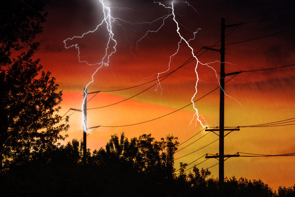 lightning strikes at sunset with a background of electrical posts