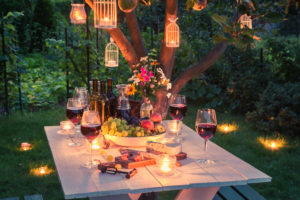 outdoor picnic table loaded for a party with the right electrical lighting around it for ambiance