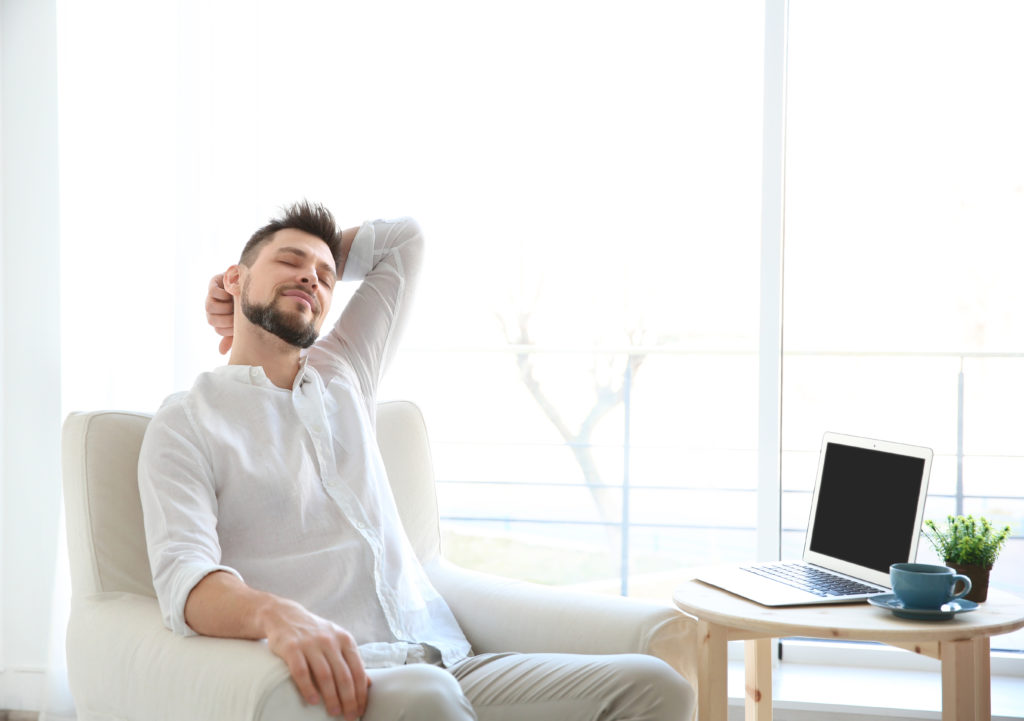 Guy in a white chair, leaning back, enjoying his temperature controlled home