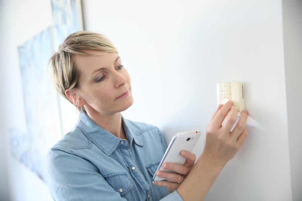 Woman programming indoor temperature with smartphone application