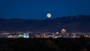 The city of Albuquerque at night with a supermoon shining brightly overhead