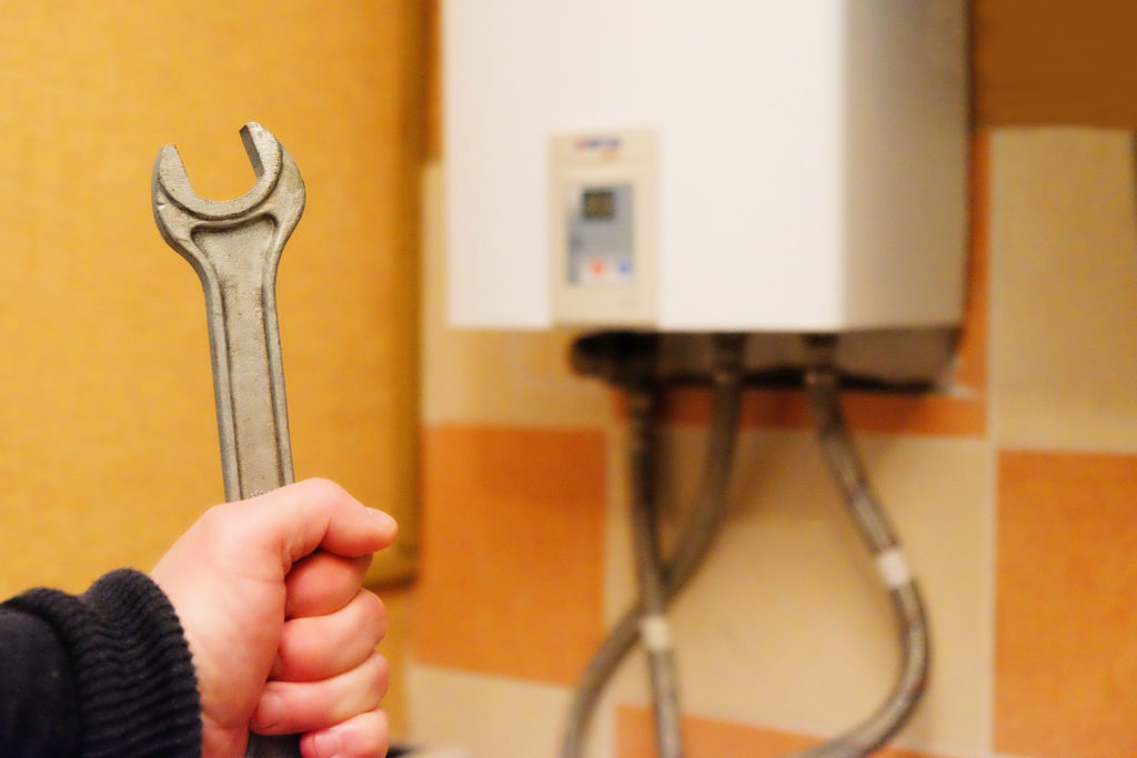 Man holding a wrench with a heating unit in the background