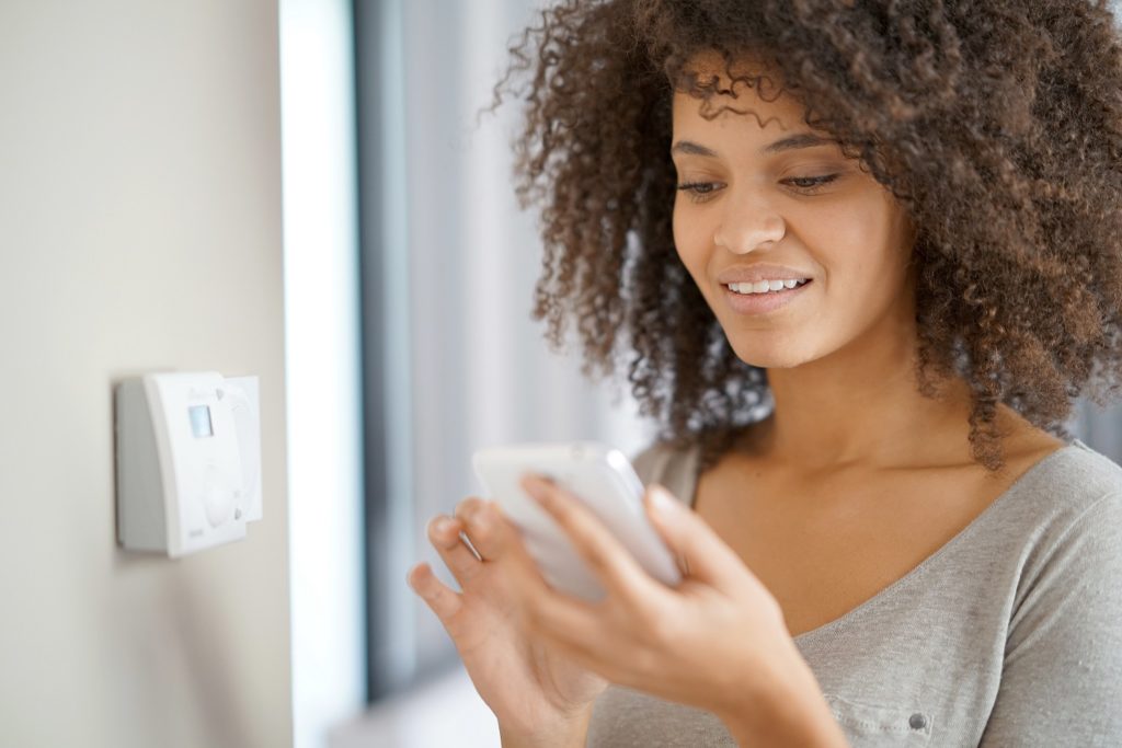 Woman controlling home temperature with electronic device