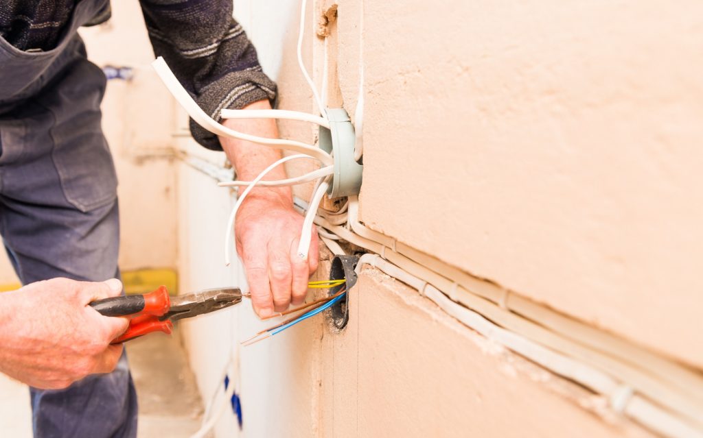 man working with pliers at house wall wires