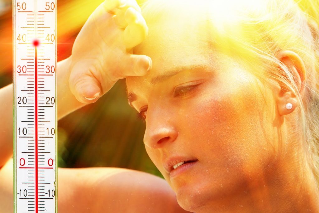 woman enduring hot temperatures with a thermometer next to her