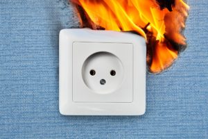 An electrical outlet begins to catch fire due to neglected faulty wiring