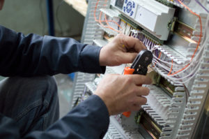 Electrician assembling industrial control cubicle in workshop.