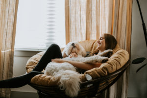 a young woman relaxing at home while holding her dog on her lap