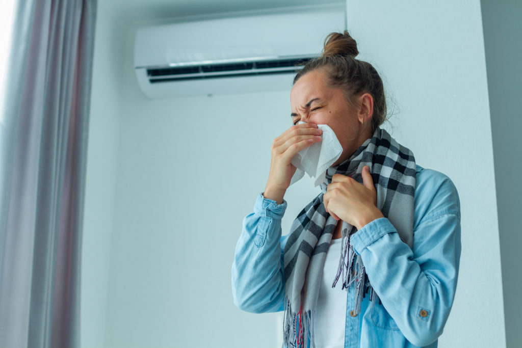 Sneezing woman caught a cold from the air conditioner at home
