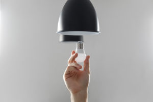 Changing the bulb for led bulb in floor lamp in black colour. On light gray background