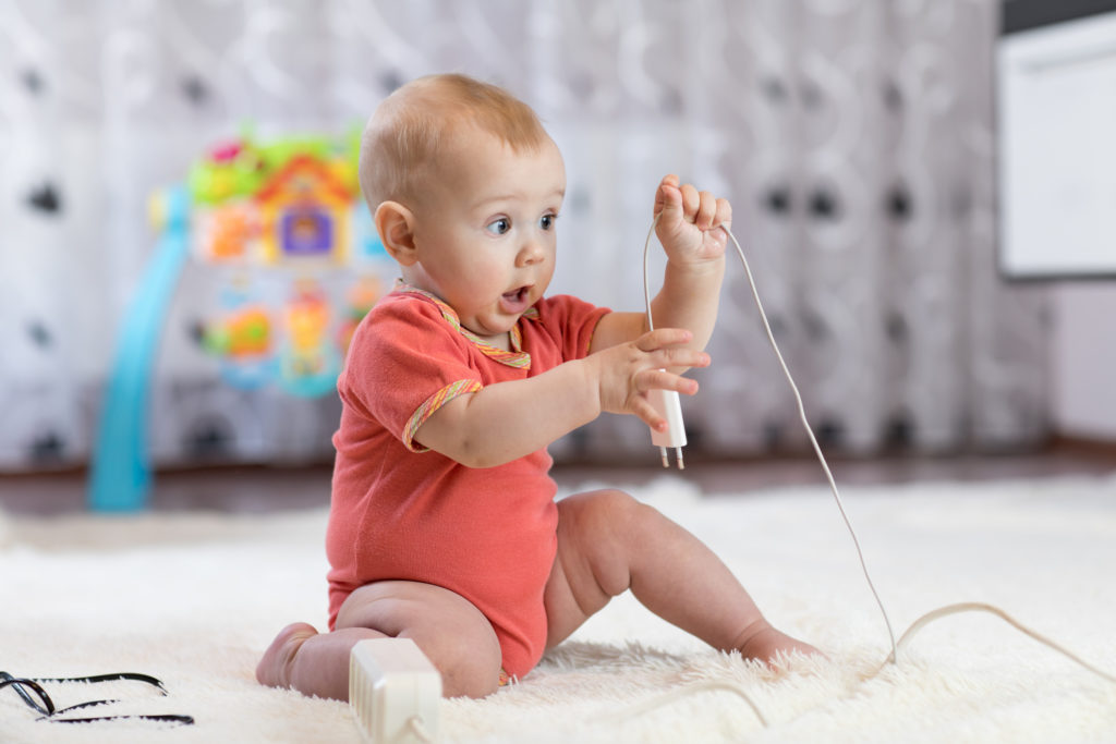 Funny baby boy pulling cables from electrical extension