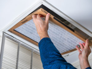 A professional inserting a new, clean filter into an HVAC system in El Paso.