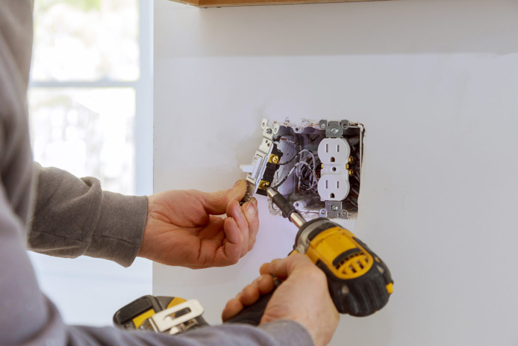 An electrician fixing an electrical socket in El Paso.