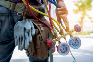 A person holding red and blue gauges for air conditioning service in El Paso.