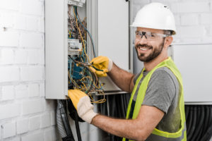A smiling electrical contractor fixing an electrical issue in El Paso.