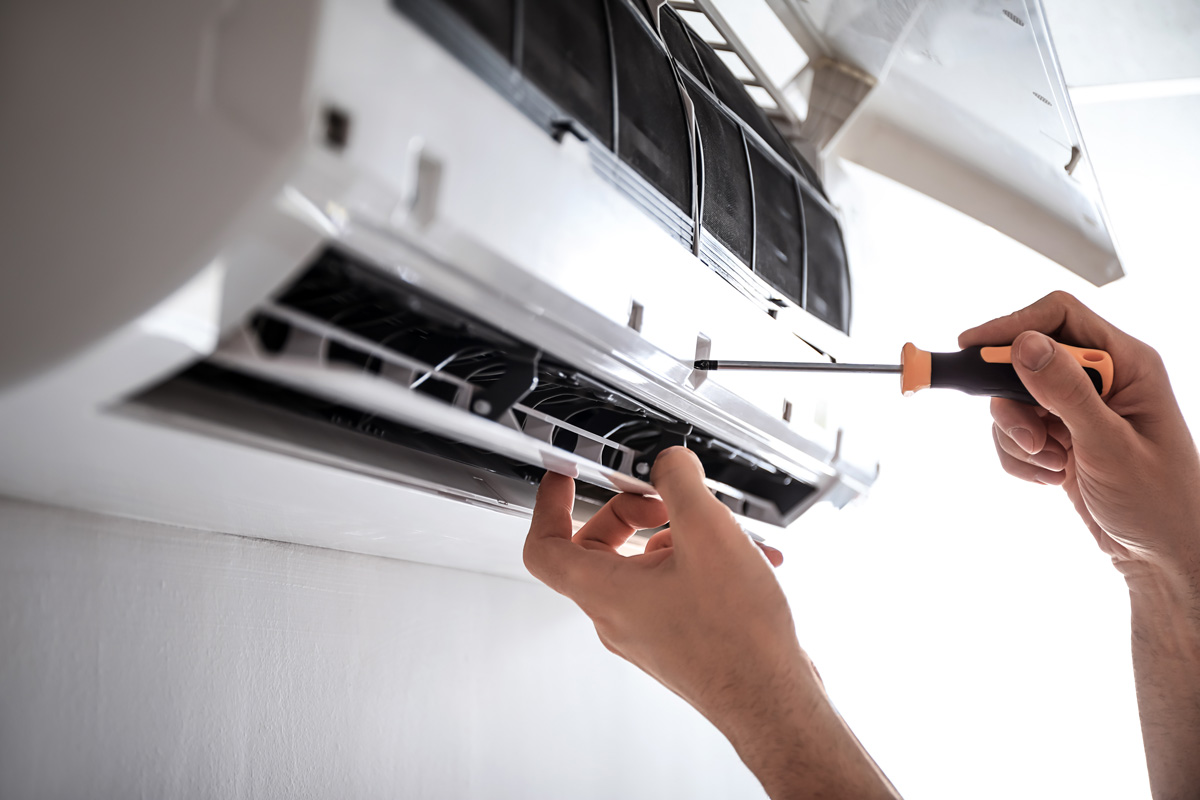 A person’s hands using a screwdriver to perform air conditioning repair in El Paso.