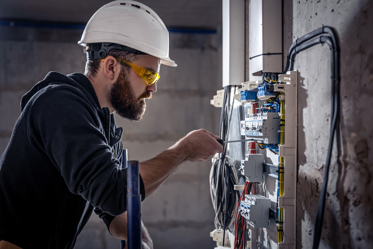 An electrician with a white hard hat performing an electrical inspection in El Paso.
