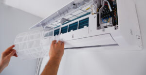 A person replacing a filter on a wall AC unit in El Paso.