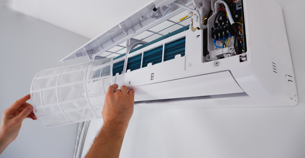 A person replacing a filter on a wall AC unit in El Paso.